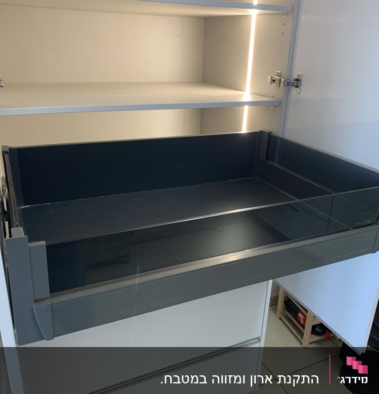 מגירה פתוחה בארון מטבח עם תאורה פנימית